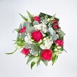 A top-down view of a full, rounded bouquet shows a joyful collision of hot pink, crisp white, and layered greens, laid out on a brilliant white background so every colour seems to glow. At the heart of the design, large ruffled carnations in vivid hot pink create a plush, almost velvety mound of petals, each frill catching the light and adding rich texture. Nestled close by are deep pink, almost fuchsia roses, some fully open with their classic spiralled centres on display, others still in tight buds that promise to unfurl over the next few days. Clusters of tiny white spray chrysanthemums form soft, daisy-like cushions between the bolder blooms, while airy sprigs of white gypsophila float over the arrangement like a delicate veil. Slender white buds, likely alstroemeria or a similar lily-like flower, peek through with an understated elegance, hinting at purity and calm. Around this colourful core, a generous collar of foliage creates structure: rounded, silvery-green eucalyptus leaves with their smooth, slightly waxy surface, bright green linear leaves that arc gently outward, and broader, darker greens folded neatly to frame the bouquet like a living border. The lighting feels clean and natural, as if the bouquet has just been set down in a bright Malden Rushett kitchen after being delivered, every detail sharp and inviting. The bouquet radiates celebration and affectionate warmth, ideal for birthdays, congratulations, or simply lifting someone's spirits on a quiet afternoon near Chessington or along Rushett Lane, offering both exuberant colour and soft, comforting texture in one considered floral gesture.